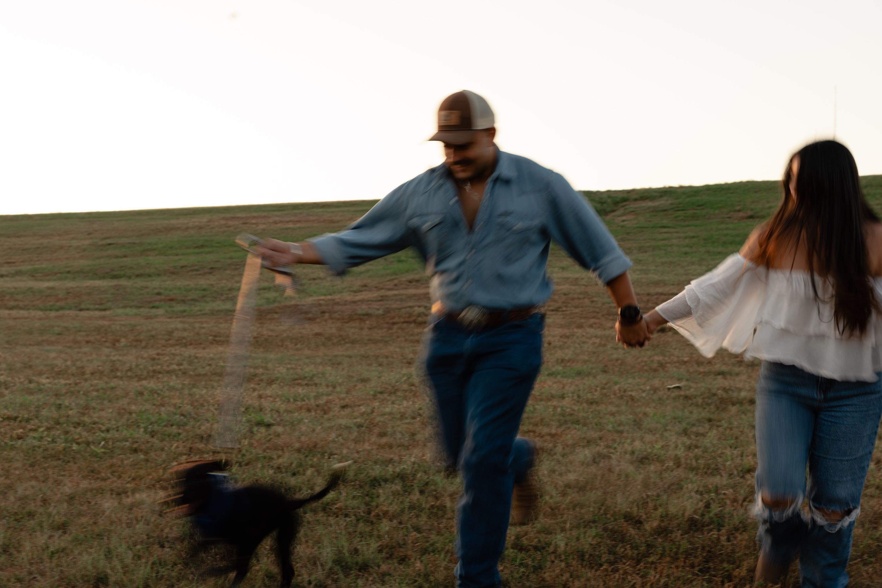 Engaged couple running hand in hand through a field, Memphis engagement photography by Atkinson Studio