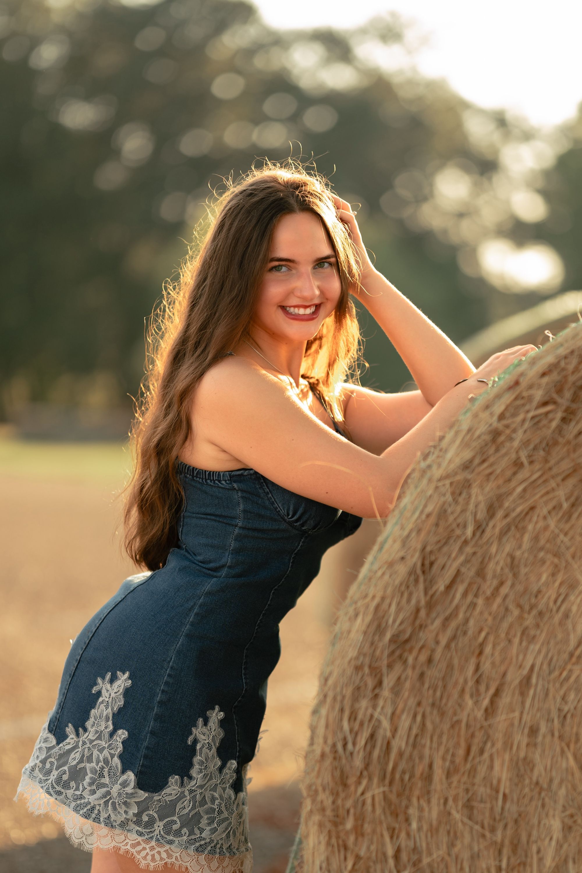 Senior portrait on a hay bale in rim light, Memphis senior portraits by Atkinson Studio