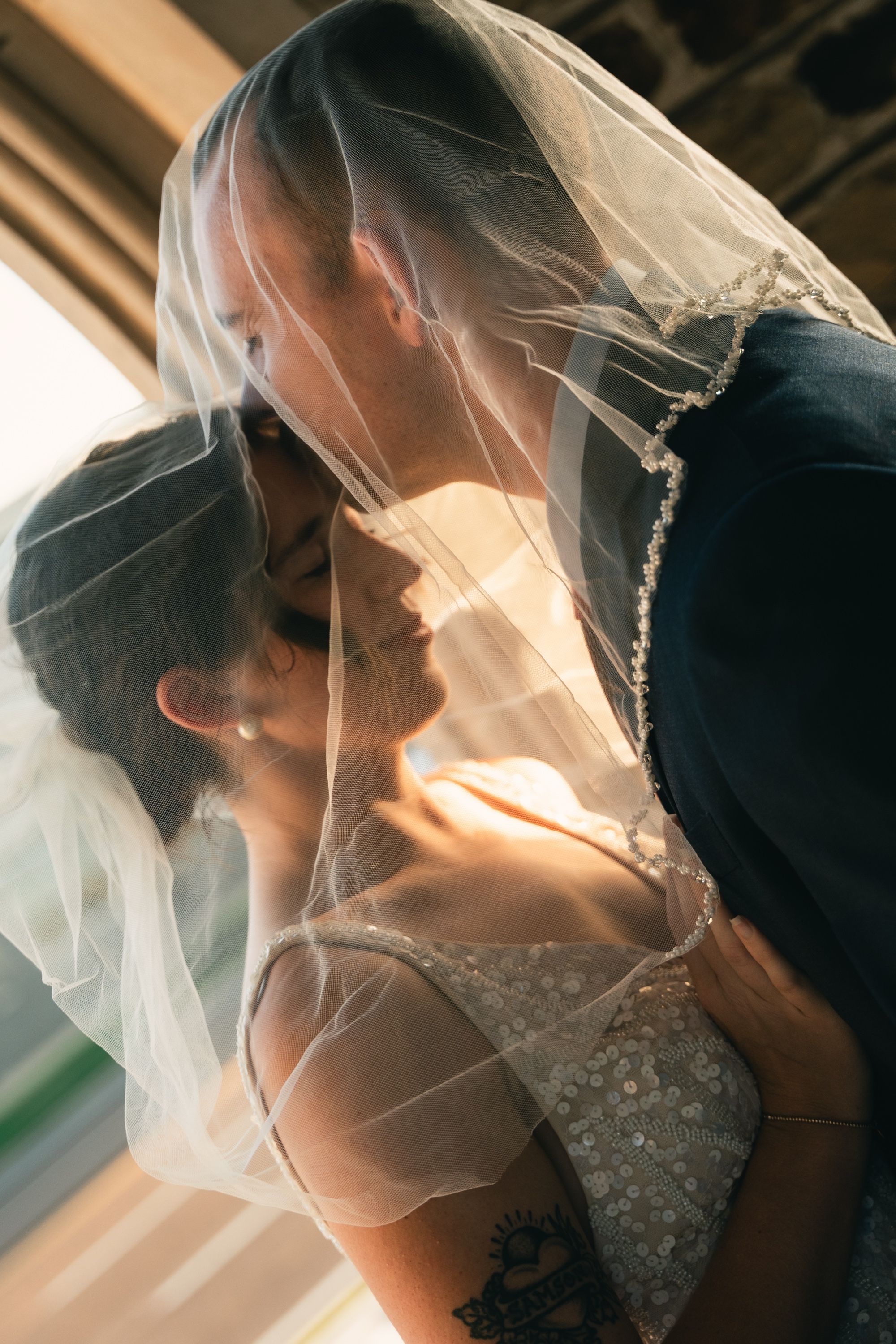 Groom kissing the bride beneath her veil in golden light, Memphis wedding photography by Atkinson Studio