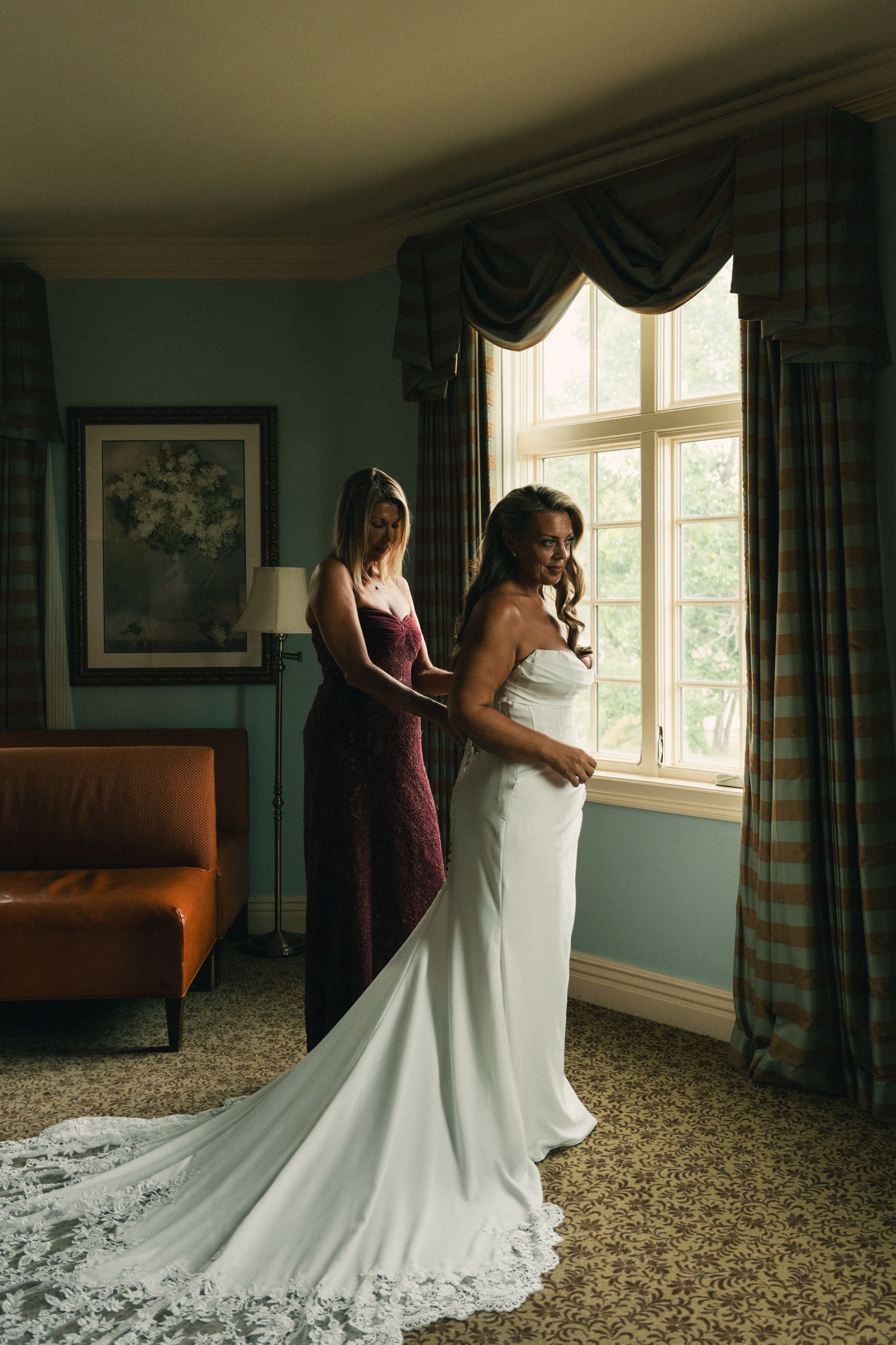 The bride's gown being buttoned beside a tall window, Memphis wedding photography by Atkinson Studio